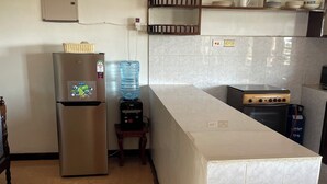 Une cuisine équipée d’un réfrigérateur en acier inoxydable, d’un distributeur d’eau, d’une cuisinière et d’un dosseret carrelé.