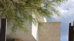 A modern building with a stone facade, a metal gate, and a view of the sea. - Seafront Apartment, ideal for Families (Torre Lapillo)