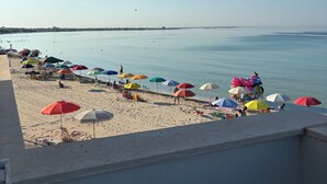 A beach with colorful umbrellas and people relaxing. - Seafront Apartment, ideal for Families (Torre Lapillo)