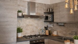 A modern kitchen with a gas stove, oven, microwave, and stainless steel sink. - Seafront Apartment, ideal for Families (Torre Lapillo)