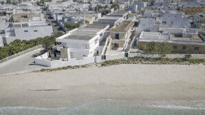 A coastal building with a flat roof, adjacent to a sandy beach. - Seafront Apartment, ideal for Families (Torre Lapillo)
