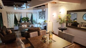 Un salon chaleureux avec une table à manger en bois, des canapés confortables et un ventilateur de plafond.