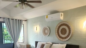 Une chambre à coucher avec un lit, un ventilateur de plafond, une fenêtre avec des rideaux et des lampes fixées au mur.