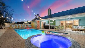 A pool area with a hot tub, lounge chairs, and a covered patio. - Sleeps 20! Pickleball, Heated Pool, Hot Tub & Games Retreat! Near Beaches (Bradenton)