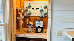 En hyggelig café med træindretning, en kaffemaskine og kopper hængende på en anslagstavle.