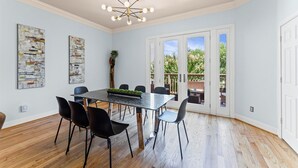 Un espace repas avec une table en marbre, des chaises noires et un lustre moderne.