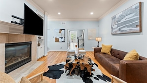 Un salon moderne avec une cheminée, un canapé en cuir et un tapis en peau de vache.