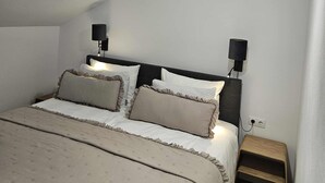 A bedroom with a bed, two wall-mounted lamps, and a geometric pendant light. - Central Apartment (Zetea)