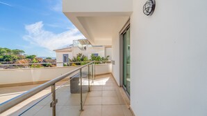A balcony with a glass door, a metal railing, and a view of the sea and greenery. - T2 Luminoso c/Piscina perto da Praia by LovelyStay (Olhos de Água)
