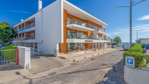 A modern multi-story hotel with balconies, a parking area, and a view of the sea. - T2 Luminoso c/Piscina perto da Praia by LovelyStay (Olhos de Água)
