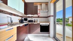 A modern kitchen with a built-in oven, microwave, and coffee maker. - T2 Luminoso c/Piscina perto da Praia by LovelyStay (Olhos de Água)