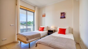 A hotel room with two beds, a balcony, and a city view. - T2 Luminoso c/Piscina perto da Praia by LovelyStay (Olhos de Água)