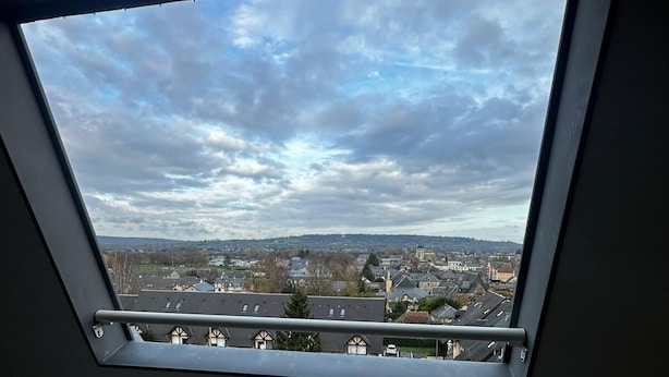 A skylight window with a view of a cityscape. - Cosy nest in pont l'évêque (pont l eveque)