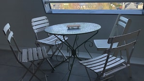 A balcony with a round metal table and four white chairs. - Cosy nest in pont l'évêque (pont l eveque)