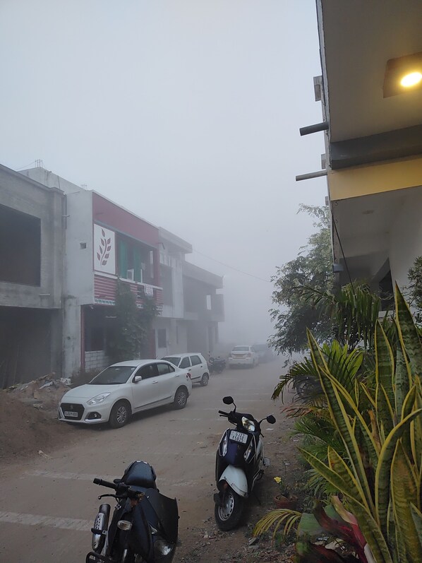 A street scene with parked vehicles and buildings. - MAHAKALI HOMESTAY (Garudeshwar)