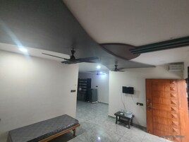 A room with a bench, ceiling fans, a tiled floor, and a wooden door.