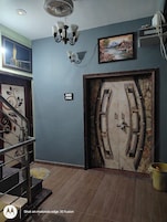 A room with a marble door, a chandelier, a framed picture, and a staircase.
