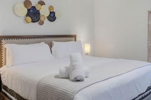 A neatly made bed with white linens, a wooden headboard, and a decorative wall piece above it. - Furnished 2BR in South Tampa | Ideal for Weekly & Extended Stays (Tampa)