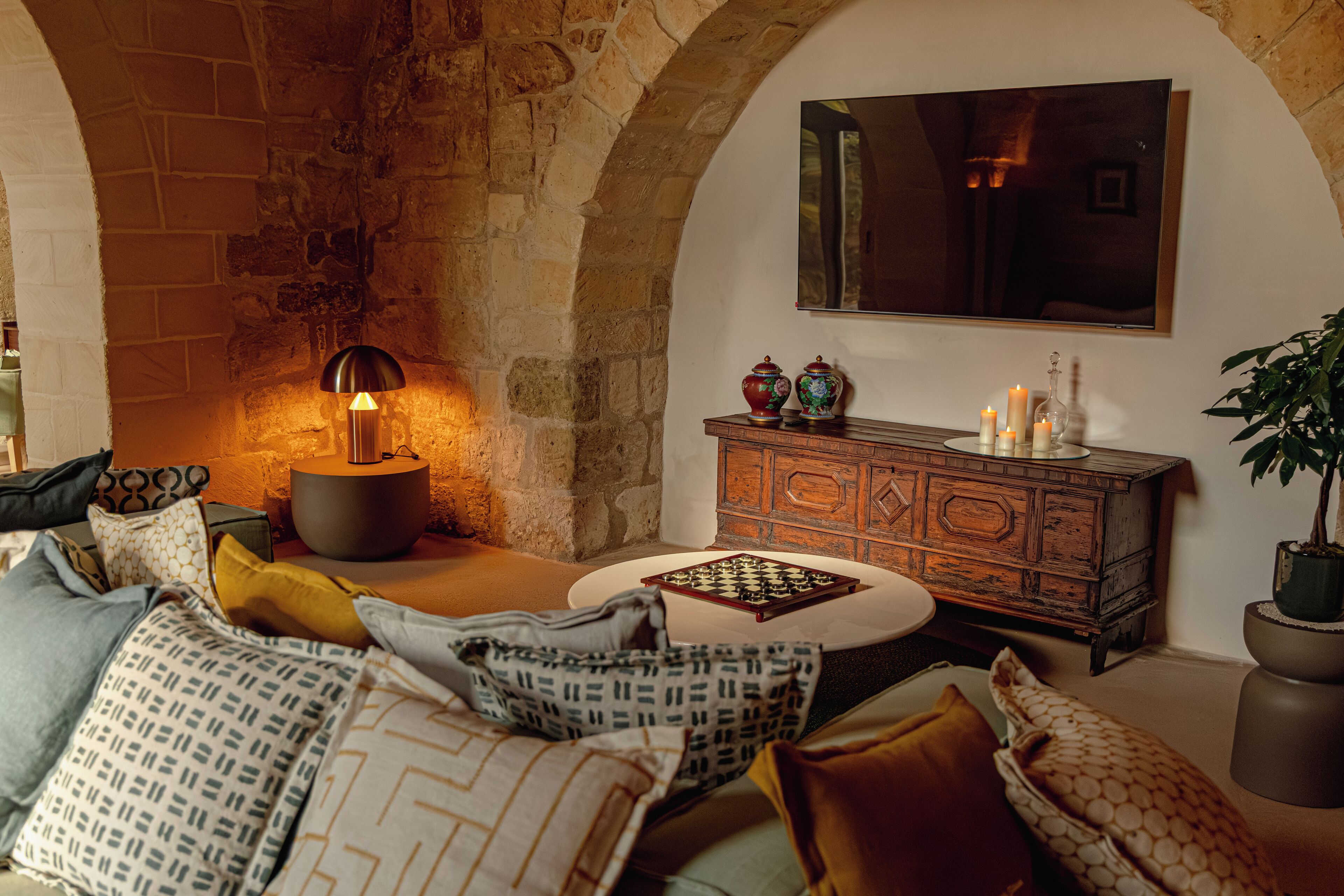A cozy living room with a stone wall, a wooden cabinet, and a round coffee table.