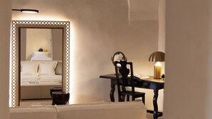 A hotel room with a mirrored wardrobe, a desk with a lamp, and a white sofa. - Masseria Eirene (Lecce)