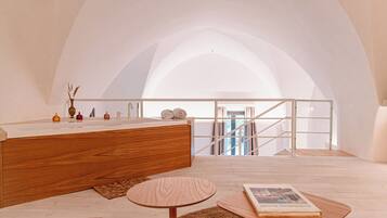 A modern bathroom with a wooden vanity, a round wooden table, and a view of a staircase.