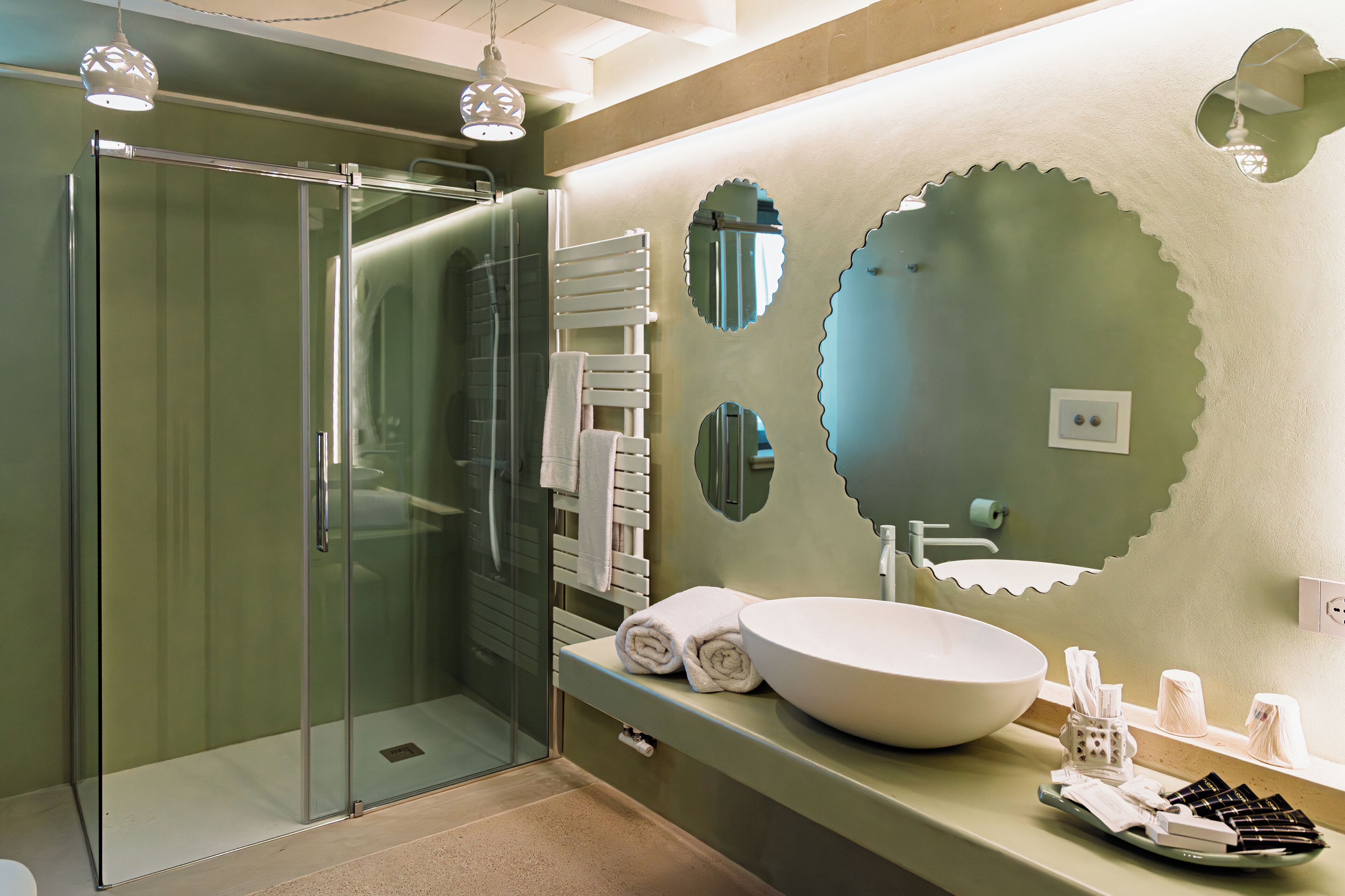 A modern bathroom with a glass-enclosed shower, a large sink, and decorative mirrors.