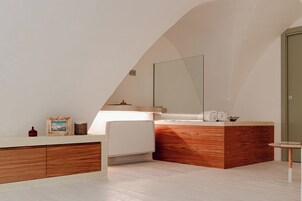 Un baño moderno con tocador de madera, un espejo grande y una mesita redonda.