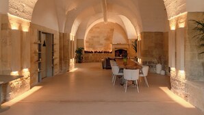 A spacious interior with a long table and chairs, stone walls, and a fireplace. - Masseria Eirene (Lecce)