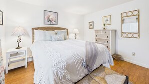 A bedroom with a large bed, a nightstand, a dresser, and a bench. - Garden Casita-Walk to Town (Arcata)