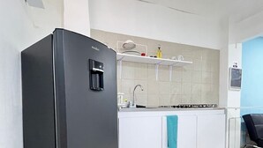 Una cucina moderna con un frigorifero nero, mobili bianchi, un lavello e un asciugamano blu appeso alla porta di un armadietto.