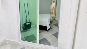 Una stanza con un letto, un bagno piccolo e una porta vetrata che dà su un balcone.