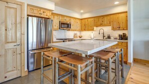 A modern kitchen with wooden cabinets, stainless steel appliances, and a central island with bar stools. - Walk to Lift! Luxe, Updated CBMR Home w/ Mtn Views (Gunnison)