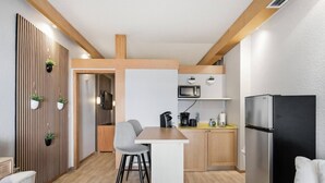 Une cuisine compacte avec un coin repas, un réfrigérateur noir et un micro-ondes fixé au mur.