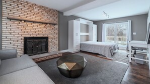 Et moderne soveværelse med en murstenspejs, en seng, et skrivebord og en balkon.