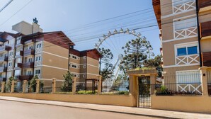 A multi-story residential building with balconies, a gated entrance, and a Ferris wheel in the background. - Modern Apartments in Canela - DAH (Canela)