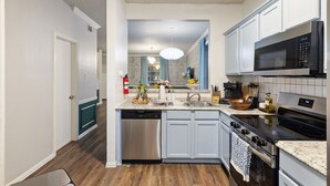 Una cocina moderna con gabinetes blancos, electrodomésticos de acero inoxidable y encimera de granito.