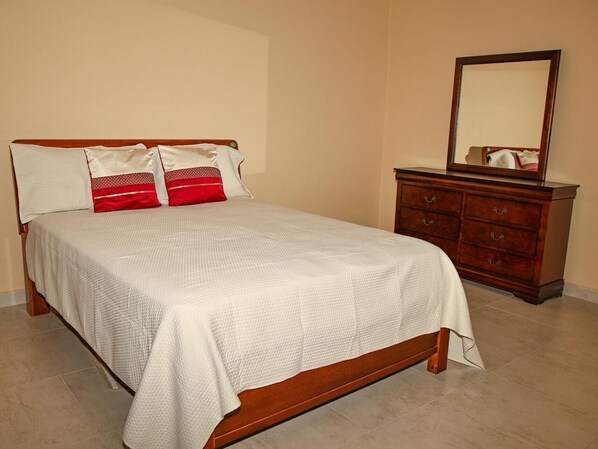 Une chambre à coucher avec un lit, une commode et un miroir.