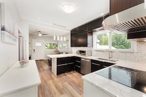 A modern kitchen with a central island, built-in appliances, and a large window providing natural light. - Modern Vancouver Home — Fast Wi-Fi & Self Check-In (Vancouver)