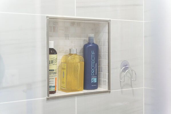 A bathroom with a glass shower enclosure containing toiletries. - Modern Vancouver Home — Fast Wi-Fi & Self Check-In (Vancouver)
