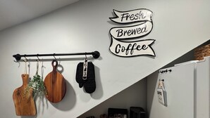 A kitchen with a sign saying "Fresh Brewed Coffee," a wooden cutting board, a knife, and a coffee maker. - Contemporary Countryside Home, Minutes to Concord (Loudon)