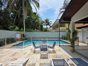 Una piscina al aire libre, sombrillas, sillones reclinables de piscina