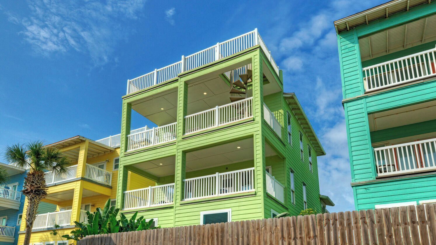 A multi-story building with balconies and a wooden fence in front.
