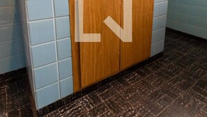 A bathroom with a blue tiled wall, a wooden cabinet, and a black marble floor.