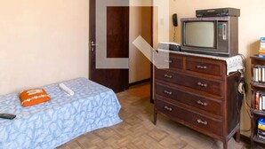 A bedroom with a bed, a dresser, a television, and a door.
