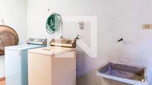 A laundry room with two washing machines, a hose, and a sink.