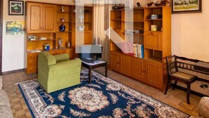 A living room with a sofa, a coffee table, a bookshelf, and a patterned rug.