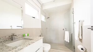 A modern bathroom with a granite countertop, a toilet, a shower, and a towel rack. - Sanctuary Sea View -S1-106- 2 bed, 2 bath (Punta Chame)