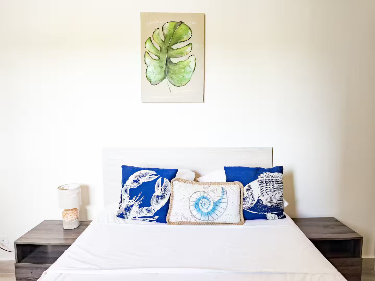 Une chambre à coucher avec un lit, une table de chevet et un tableau accroché au mur.