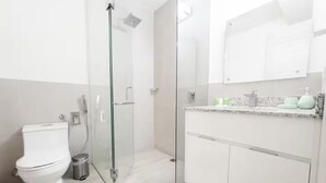Un baño moderno con cabina de ducha acristalada, inodoro y tocador con encimera de mármol.