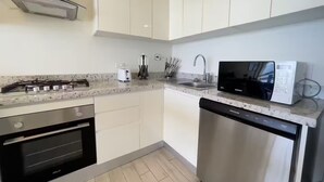 A modern kitchen with white cabinets, stainless steel appliances, a microwave, and a dishwasher. - Sanctuary Reef -S2-507- 2 bed, 2 bath (Punta Chame)